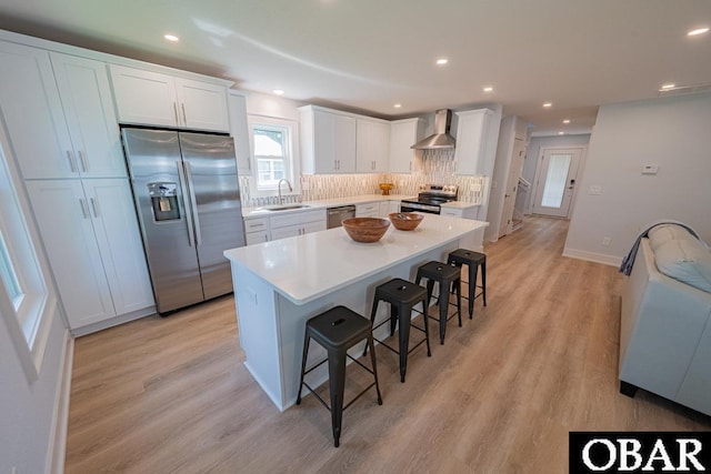 224 W Lost Colony Dr Lot 13, Nags Head, NC 27959 - kitchen with appliances with stainless steel finishes, wall chimney exhaust hood, a breakfast bar, light wood-type flooring, and tasteful backsplash