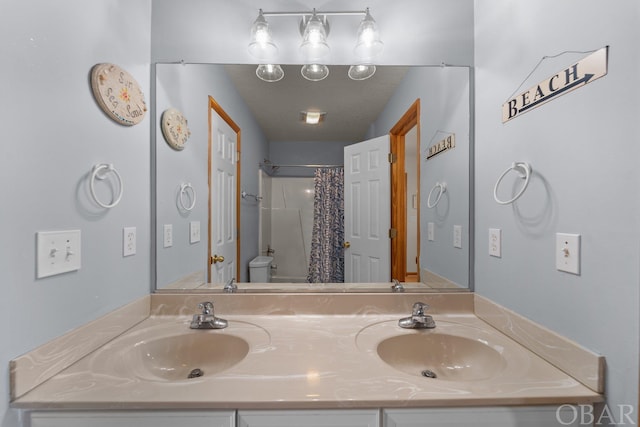 bathroom featuring toilet, a sink, a shower with shower curtain, and double vanity