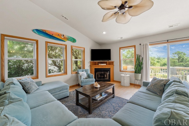 living area featuring visible vents, vaulted ceiling, a fireplace, and wood finished floors