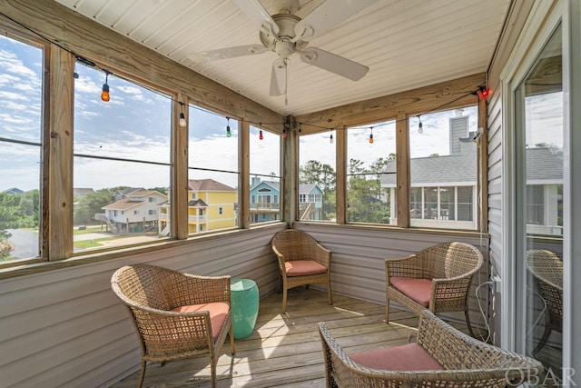 sunroom / solarium with a residential view and a ceiling fan