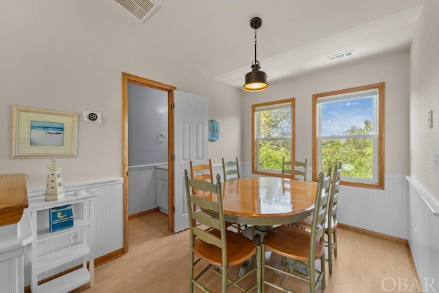 dining area featuring a wainscoted wall, visible vents, and light wood-style floors