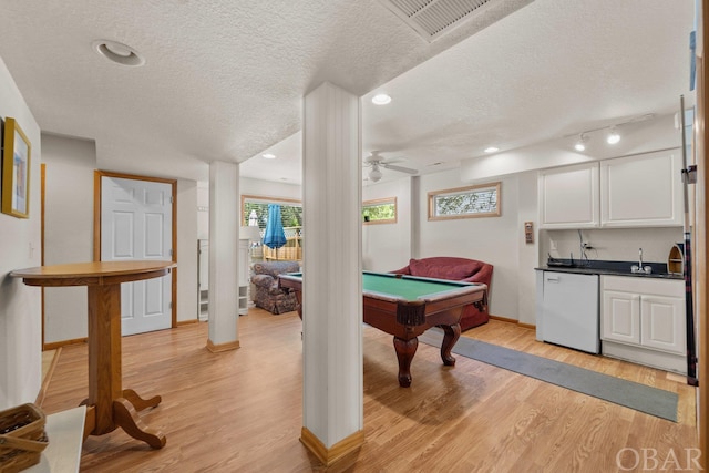 playroom featuring light wood-style floors, wet bar, a textured ceiling, and pool table