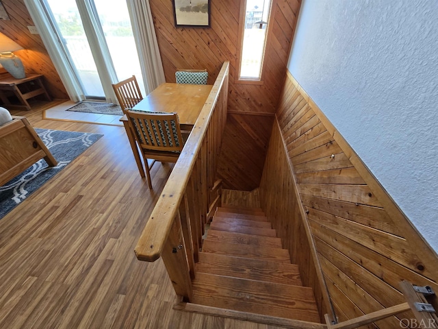 stairway featuring a textured wall, wood finished floors, and wooden walls