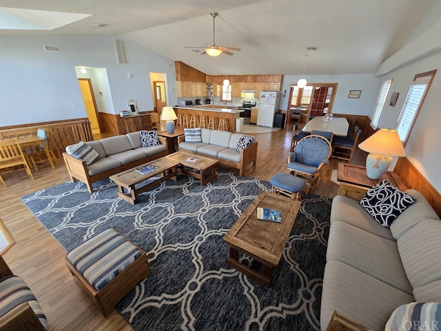 living room with lofted ceiling, light wood-style flooring, visible vents, and a ceiling fan