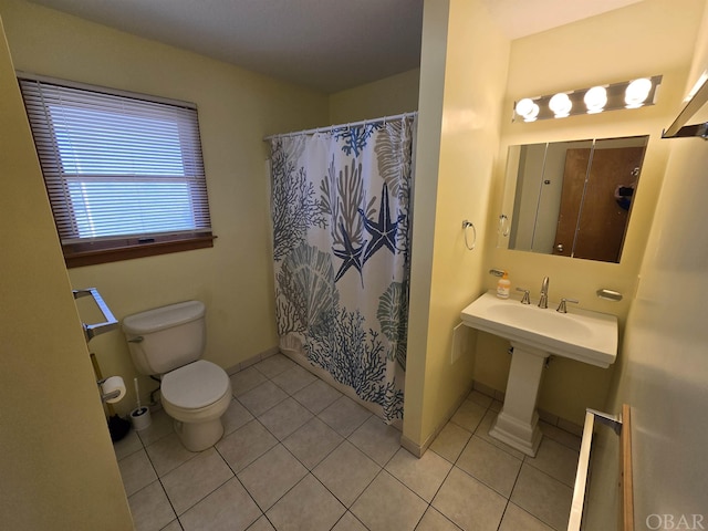 bathroom with baseboards, toilet, tile patterned floors, curtained shower, and a sink