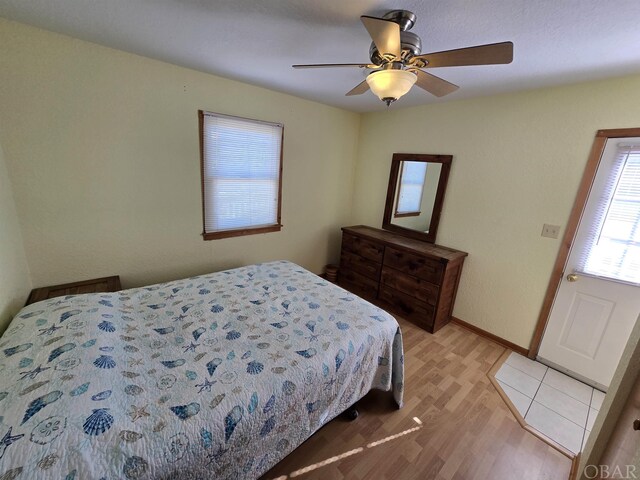 bedroom with baseboards, a ceiling fan, and light wood-style floors