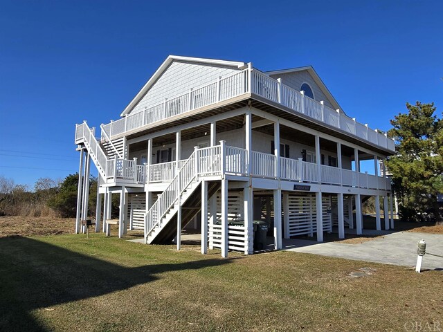 rear view of house featuring covered porch, a lawn, and stairs