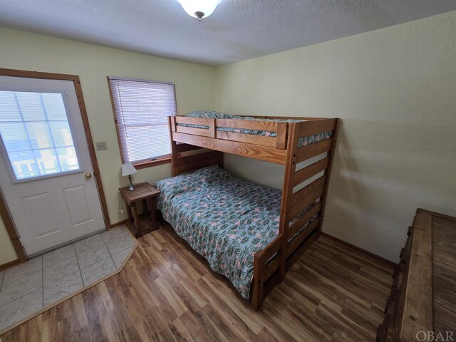 bedroom with a textured ceiling, baseboards, and wood finished floors