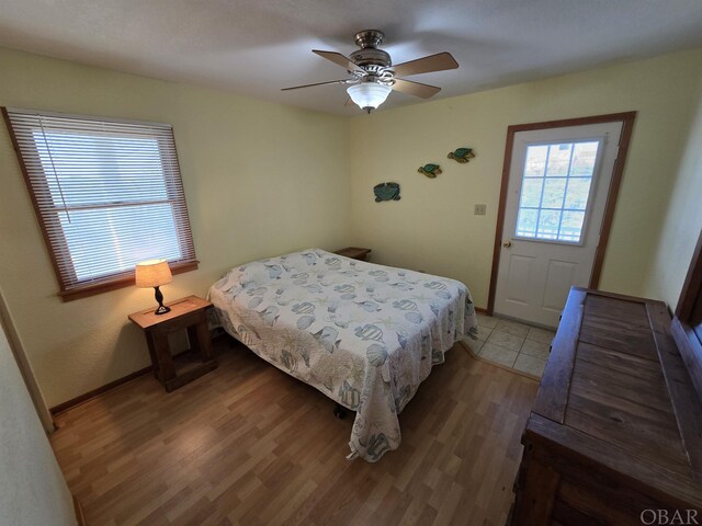 bedroom with a ceiling fan, baseboards, and wood finished floors