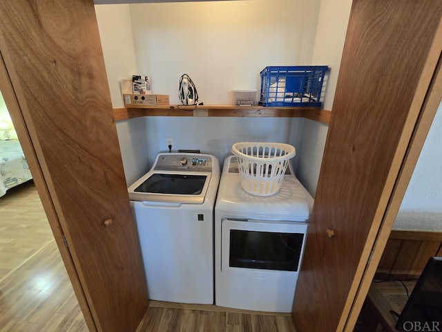 washroom with laundry area, wood finished floors, and separate washer and dryer