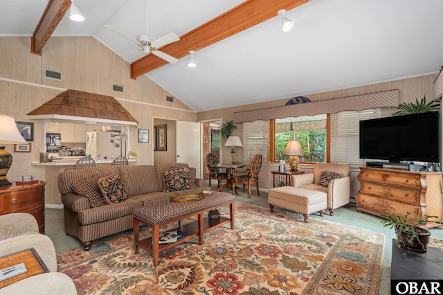 carpeted living area featuring visible vents, ceiling fan, beam ceiling, and wood walls