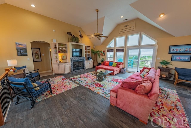 living room featuring arched walkways, high vaulted ceiling, recessed lighting, dark wood-type flooring, and a fireplace