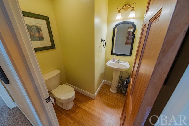 bathroom featuring a sink, wood finished floors, toilet, and baseboards