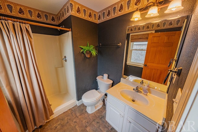 bathroom with a stall shower, vanity, and toilet