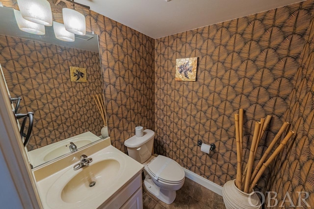 half bathroom featuring wallpapered walls, baseboards, toilet, tile patterned floors, and vanity