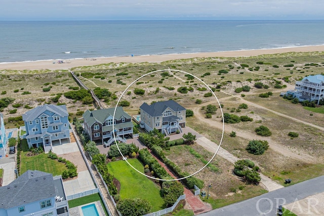 birds eye view of property with a water view and a beach view