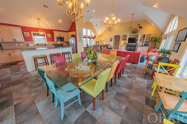 dining space with a chandelier, a healthy amount of sunlight, a fireplace, and visible vents