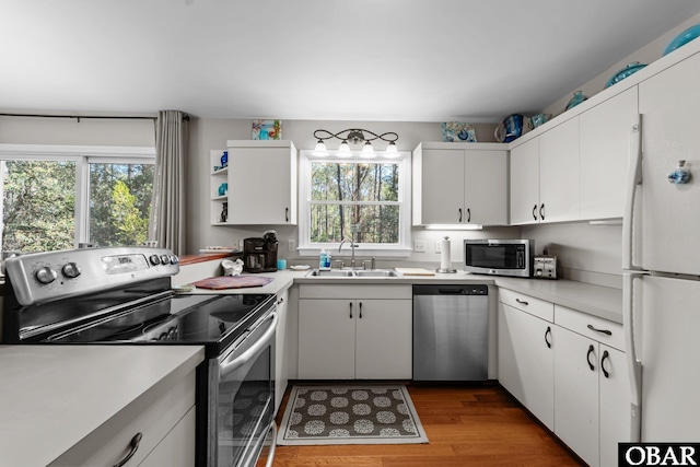 kitchen with a sink, stainless steel appliances, white cabinets, and light countertops