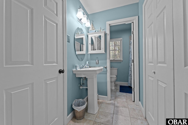 bathroom featuring tile patterned floors, baseboards, and toilet