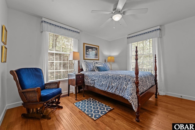 bedroom with multiple windows, a ceiling fan, baseboards, and hardwood / wood-style floors