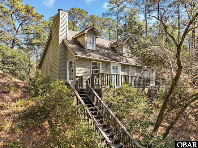 back of property featuring stairs, a deck, and a chimney