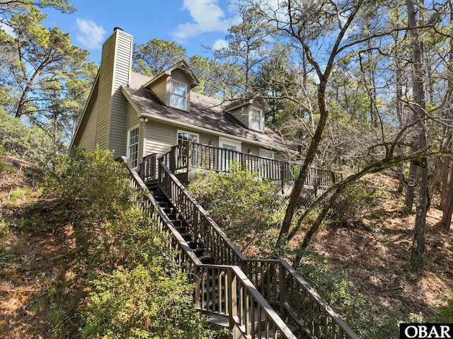 view of side of home with stairway and a chimney