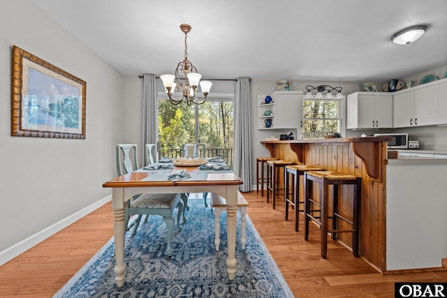 dining area with a notable chandelier, baseboards, and light wood-style floors