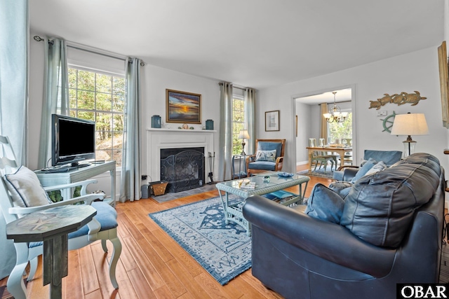 living room with a notable chandelier, a fireplace with flush hearth, and wood finished floors