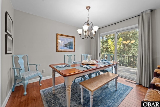 dining room featuring visible vents, baseboards, an inviting chandelier, and wood finished floors