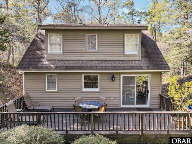 back of property with a deck and roof with shingles