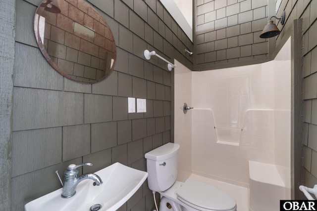 bathroom featuring a sink, walk in shower, toilet, and tile walls