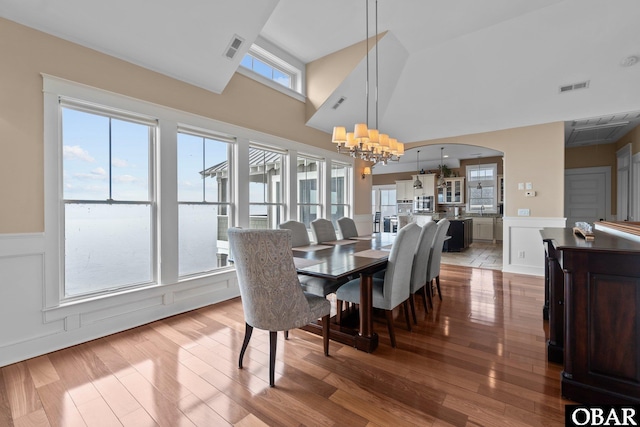 dining room with wainscoting, wood finished floors, visible vents, and a notable chandelier