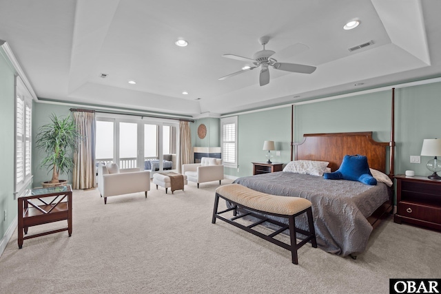 bedroom featuring light carpet, visible vents, a raised ceiling, and recessed lighting