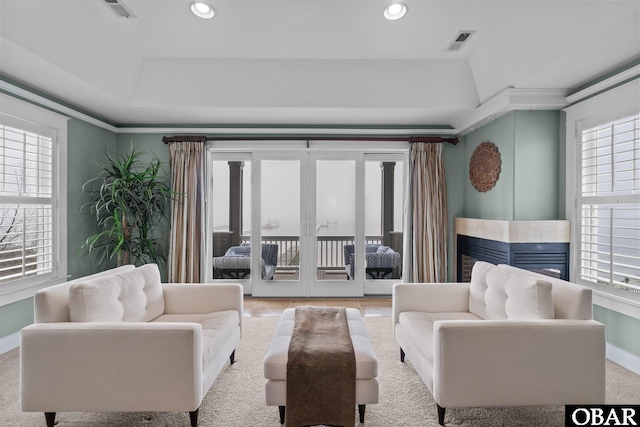 living area featuring recessed lighting, a raised ceiling, visible vents, and baseboards