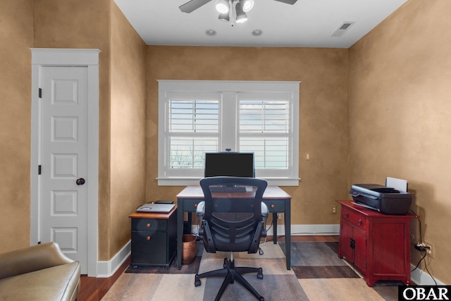 office space featuring dark wood-style flooring, visible vents, ceiling fan, and baseboards