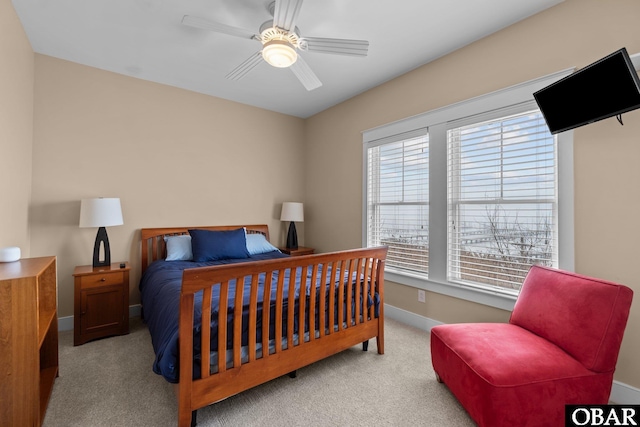 bedroom with a ceiling fan, light carpet, and baseboards