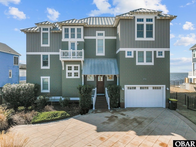 view of front of house with a water view, a standing seam roof, metal roof, and decorative driveway