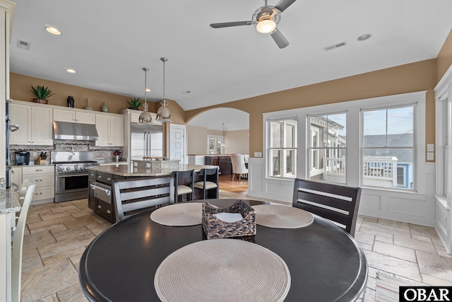 dining area with arched walkways, recessed lighting, visible vents, a ceiling fan, and stone tile flooring