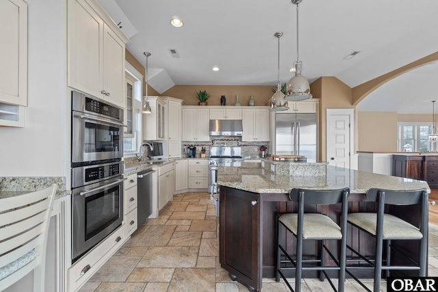 kitchen featuring premium appliances, a center island, vaulted ceiling, and hanging light fixtures