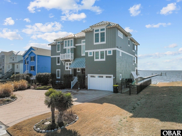 view of front of property with concrete driveway, a water view, an attached garage, a standing seam roof, and metal roof