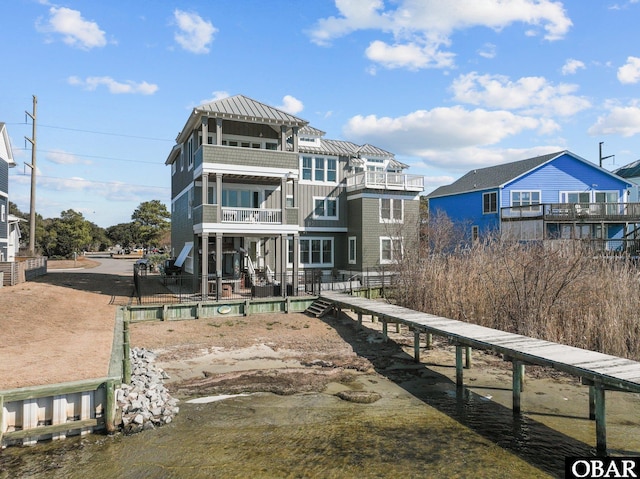 back of house featuring a standing seam roof, fence, and a balcony