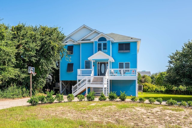 beach home with a porch, stairway, and a front yard