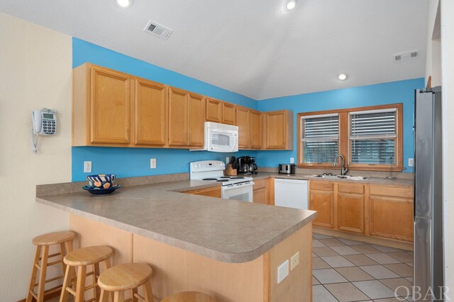 kitchen featuring white appliances, visible vents, a breakfast bar area, a peninsula, and a sink