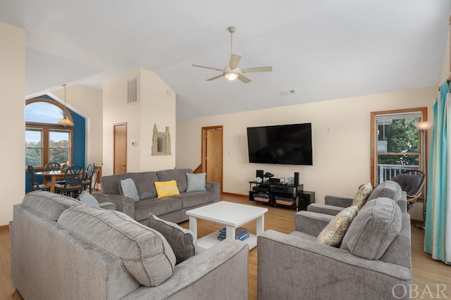 living room featuring lofted ceiling, light wood finished floors, visible vents, and a ceiling fan