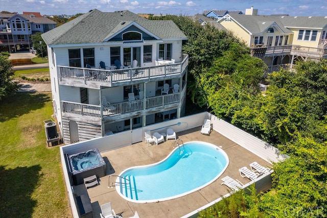 back of property with a hot tub, a patio, a balcony, a residential view, and a community pool