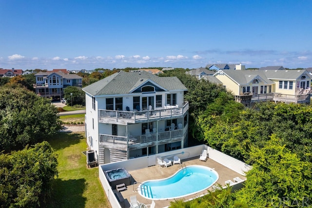 back of property featuring a balcony, a community pool, a residential view, and a patio