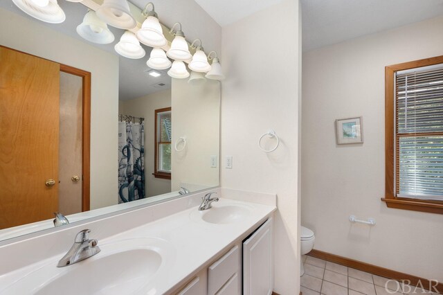 bathroom featuring baseboards, a sink, toilet, and tile patterned floors