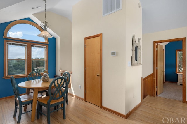 dining area featuring light wood-style floors, visible vents, and high vaulted ceiling