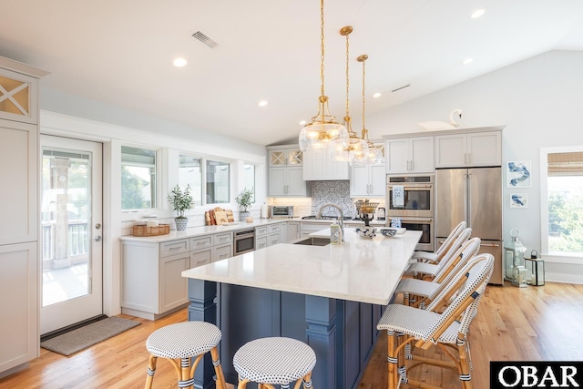 123 Skimmer Way Lot 48, Duck, NC 27949 - kitchen featuring appliances with stainless steel finishes, backsplash, lofted ceiling, a kitchen breakfast bar, and light wood-style flooring