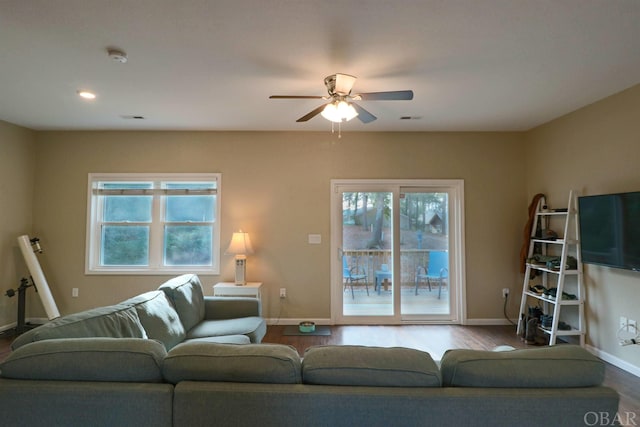 living area with a wealth of natural light, visible vents, baseboards, and wood finished floors